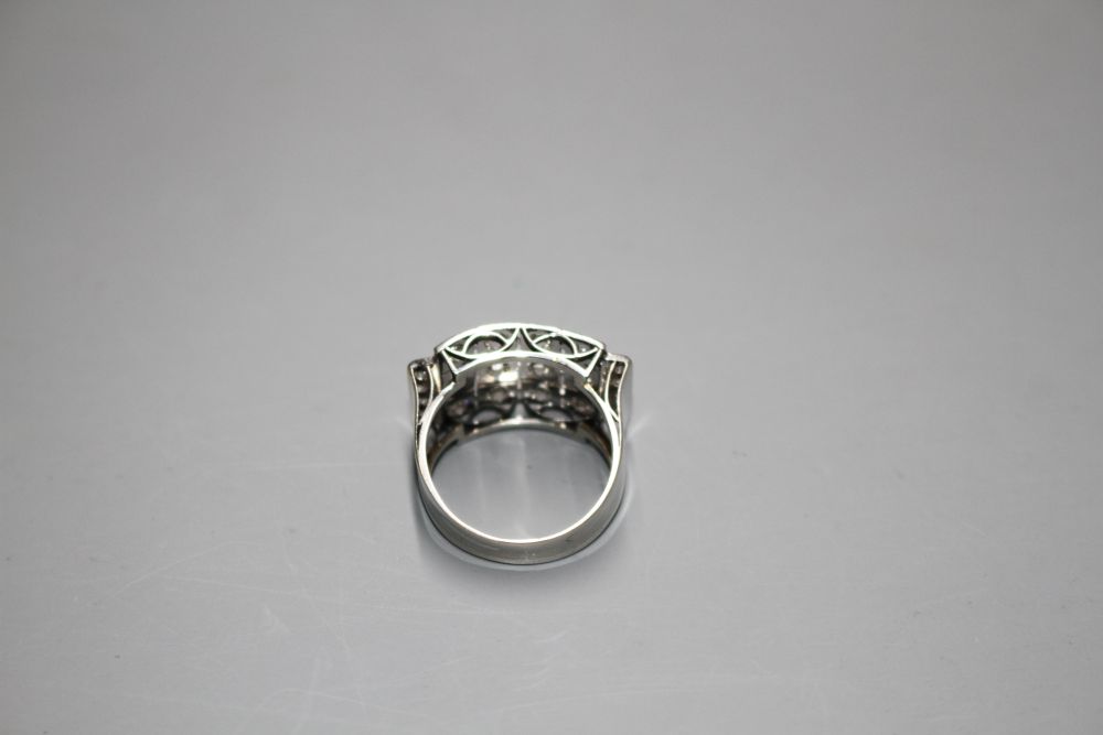 A white metal (stamped 750 and Pt 950) and pave diamond set cocktail ring, of curved design and set with twenty round cut stones.